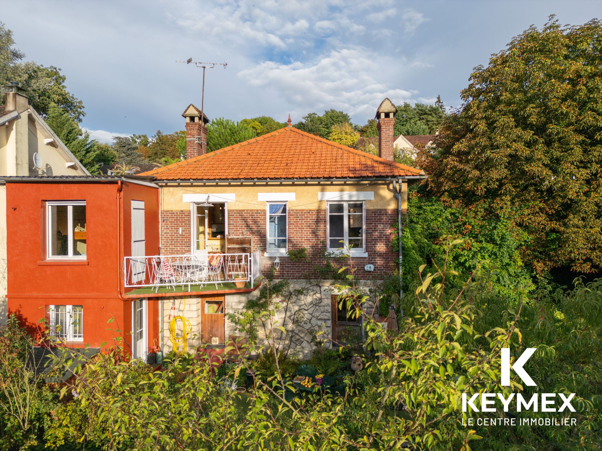 Maison en brique avec jardin verdoyant.