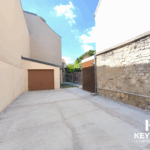 Allée avec garage fermé en journée ensoleillée.