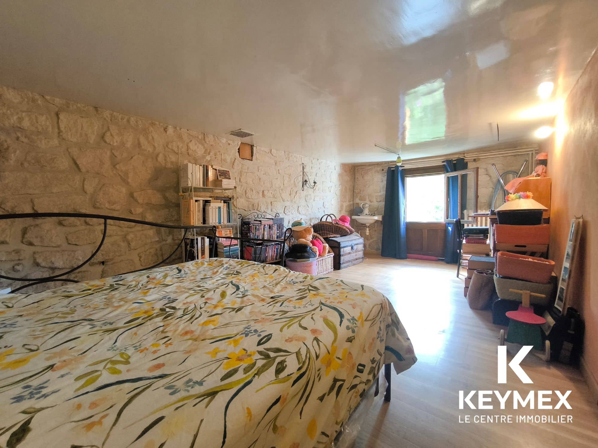 Chambre en pierre avec lit et étagères.