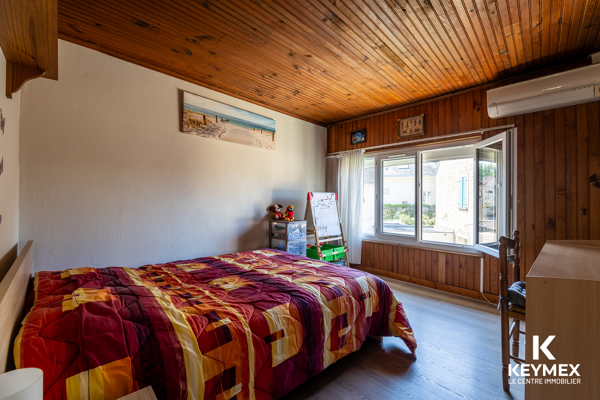 Chambre avec lit et plafond bois.