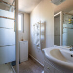 Salle de bain moderne avec douche et lavabo blancs.
