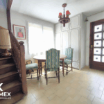 Salon lumineux avec escalier en bois.