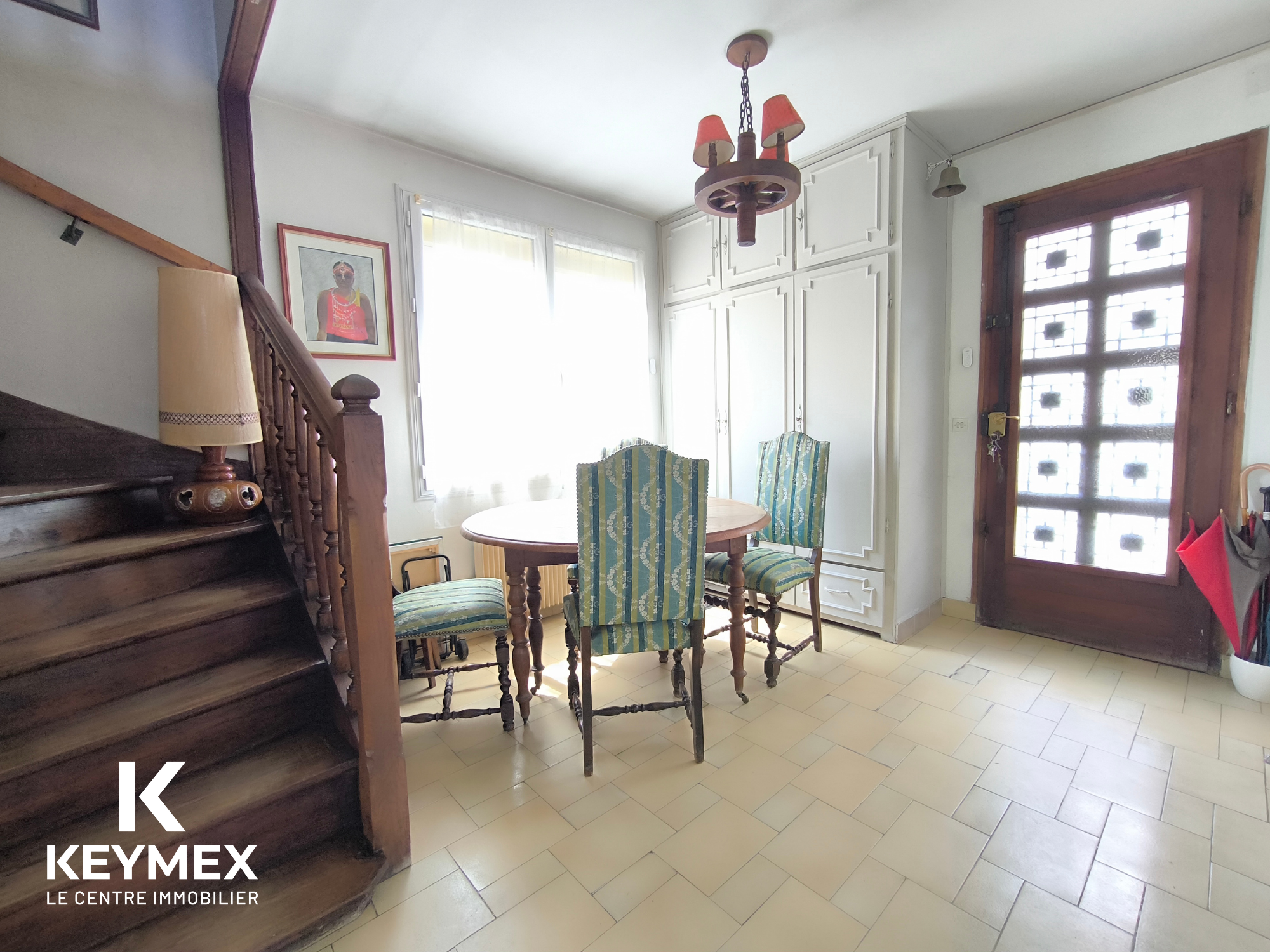 Salon lumineux avec escalier en bois.