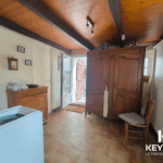 Intérieur lumineux avec meuble ancien et porte ouverte.