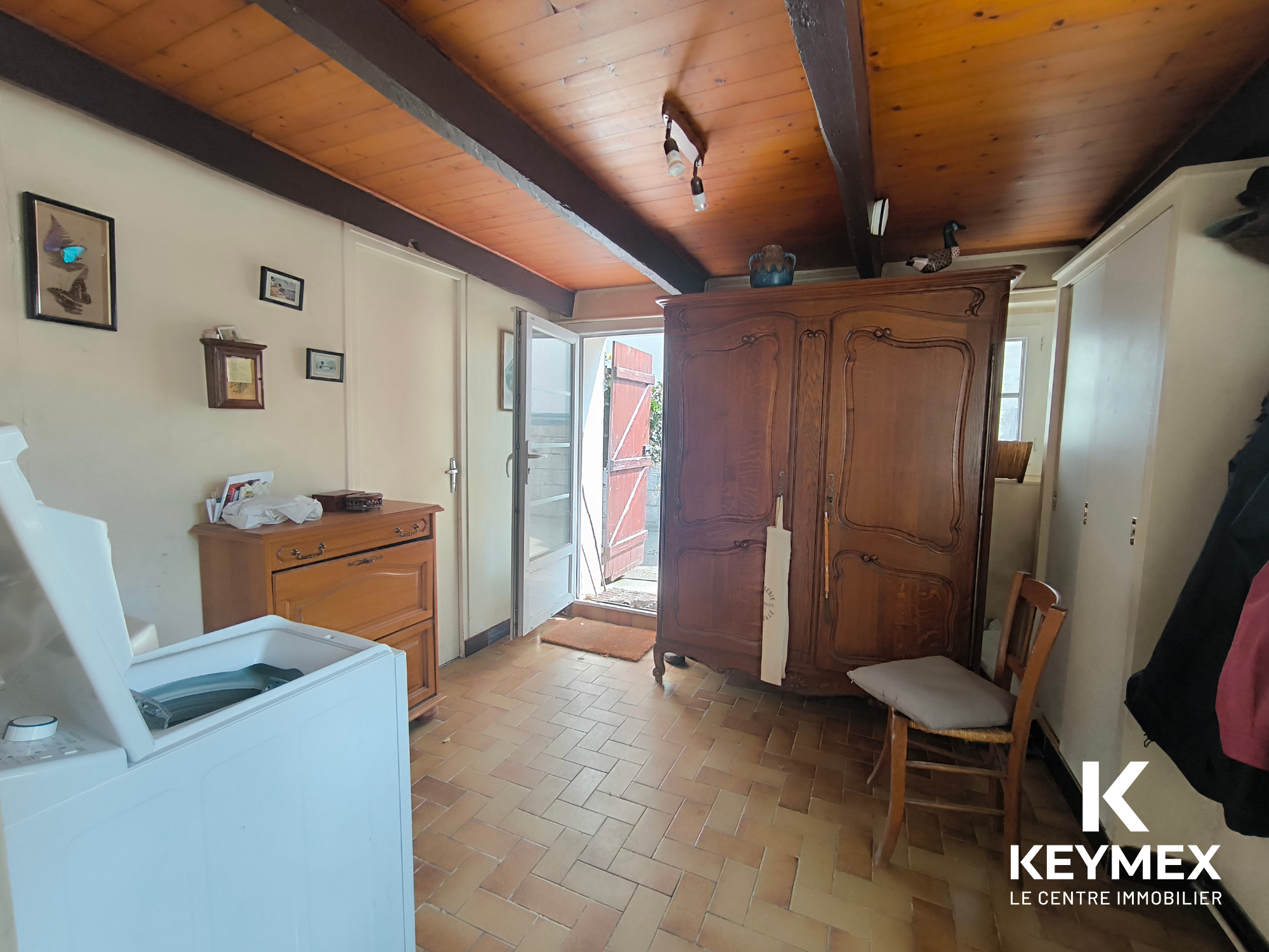 Intérieur lumineux avec meuble ancien et porte ouverte.