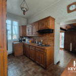 Cuisine ancienne avec meubles en bois et carrelage marron.