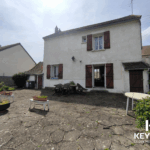 Maison avec terrasse en pierre et meubles de jardin.