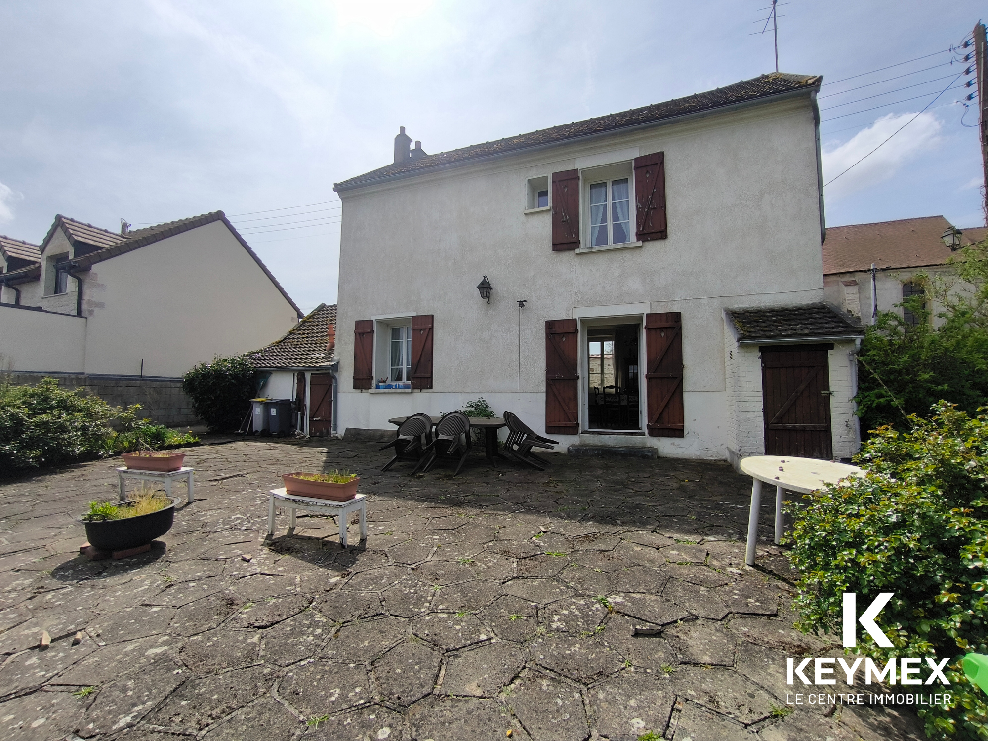 Maison avec terrasse en pierre et meubles de jardin.