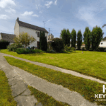 Jardin verdoyant avec maison et allée en béton.