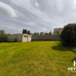 Jardin avec garage et mur en briques.