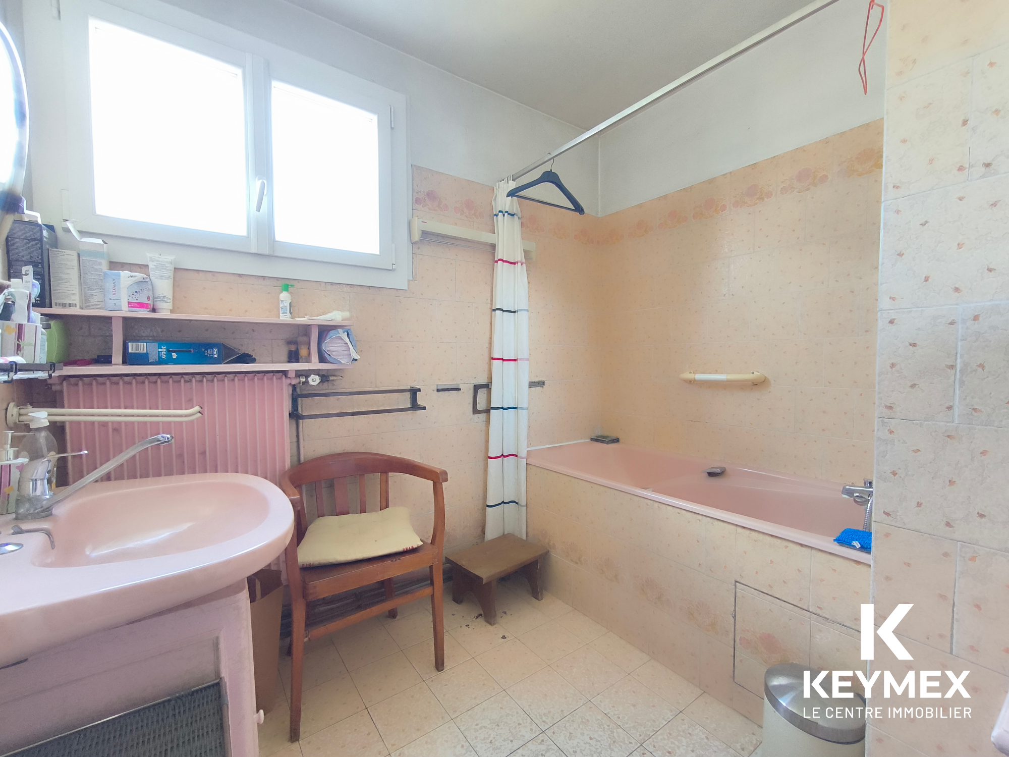 Salle de bain ancienne avec baignoire et fenêtre.