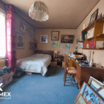 Chambre avec bureau, décorée de tableaux et étagères.