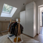 Chambre mansardée avec fenêtre de toit et penderie.