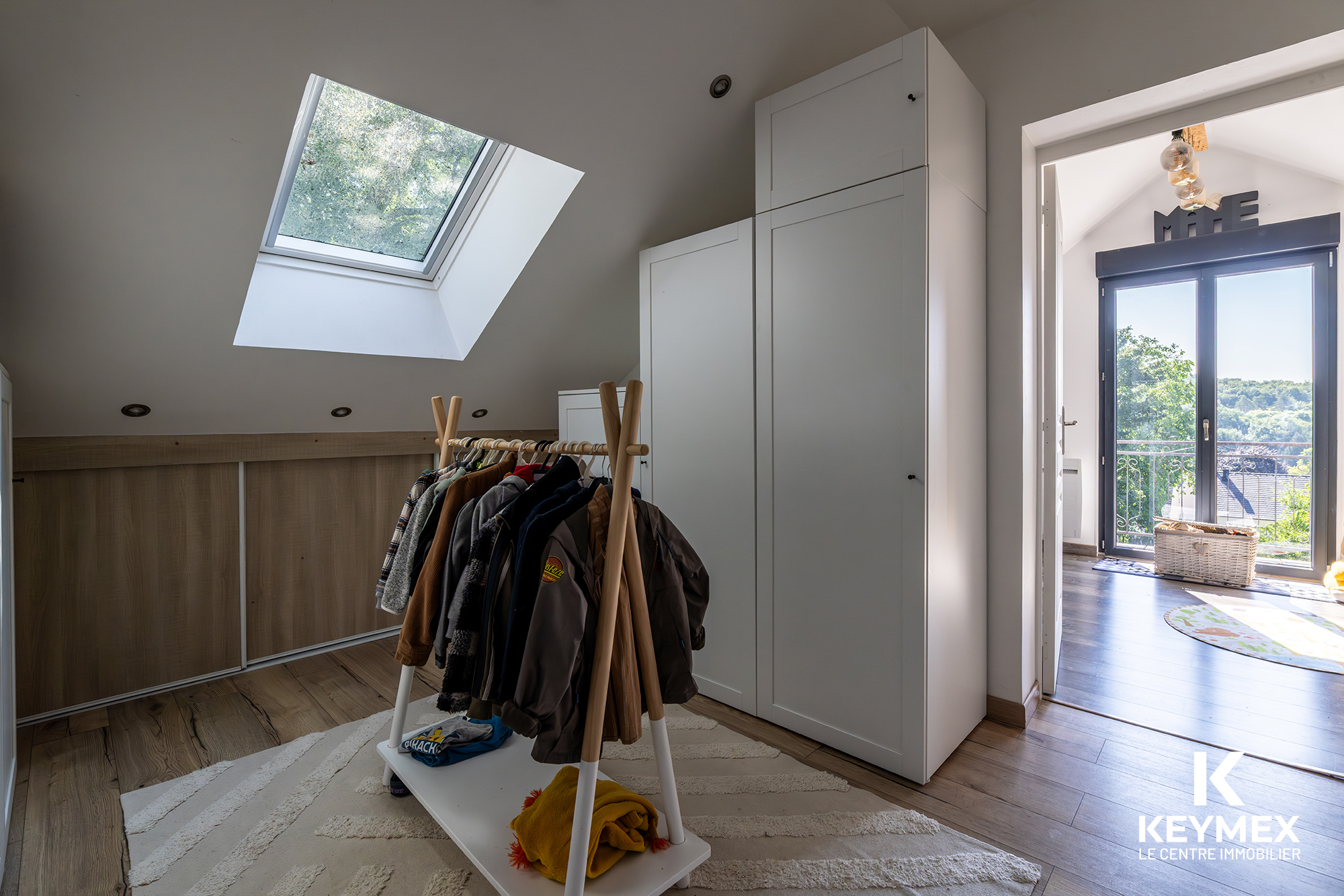 Chambre mansardée avec fenêtre de toit et penderie.