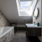 Salle de bain moderne sous toit avec baignoire.
