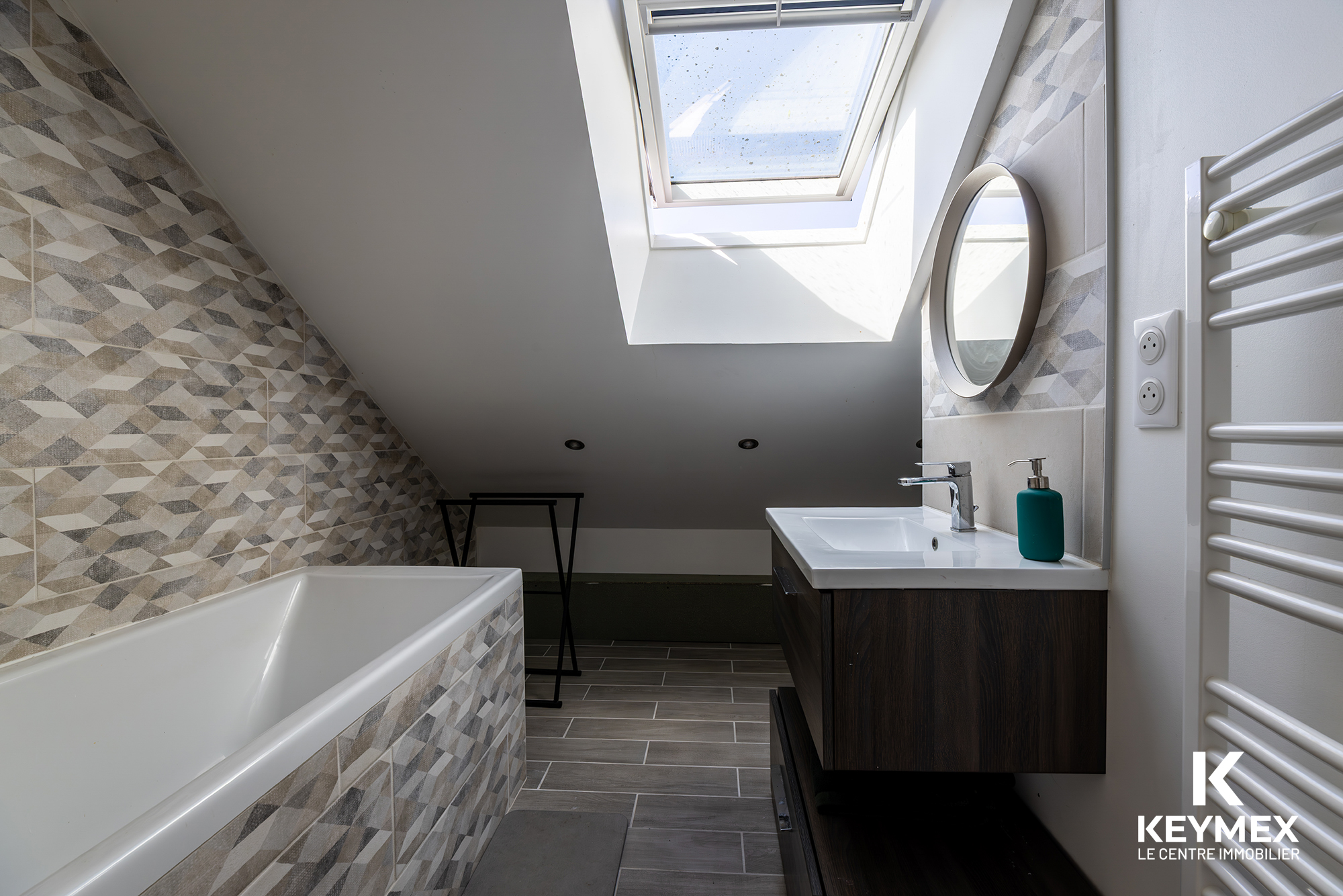Salle de bain moderne sous toit avec baignoire.