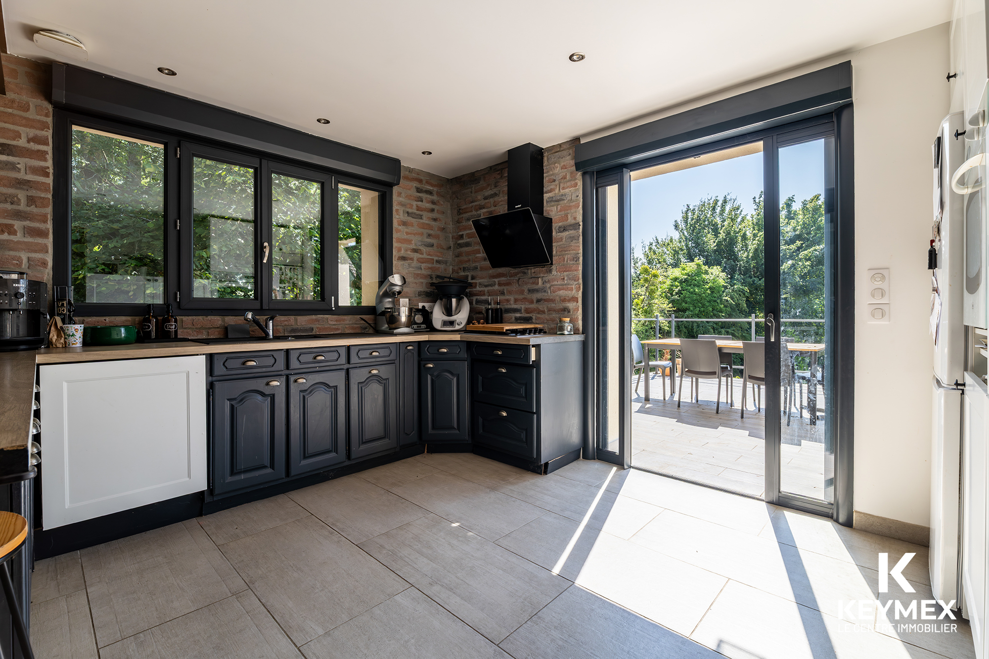Cuisine moderne avec terrasse ensoleillée extérieure.