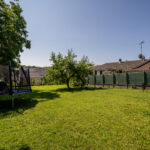 Jardin avec trampoline et maisons en arrière-plan