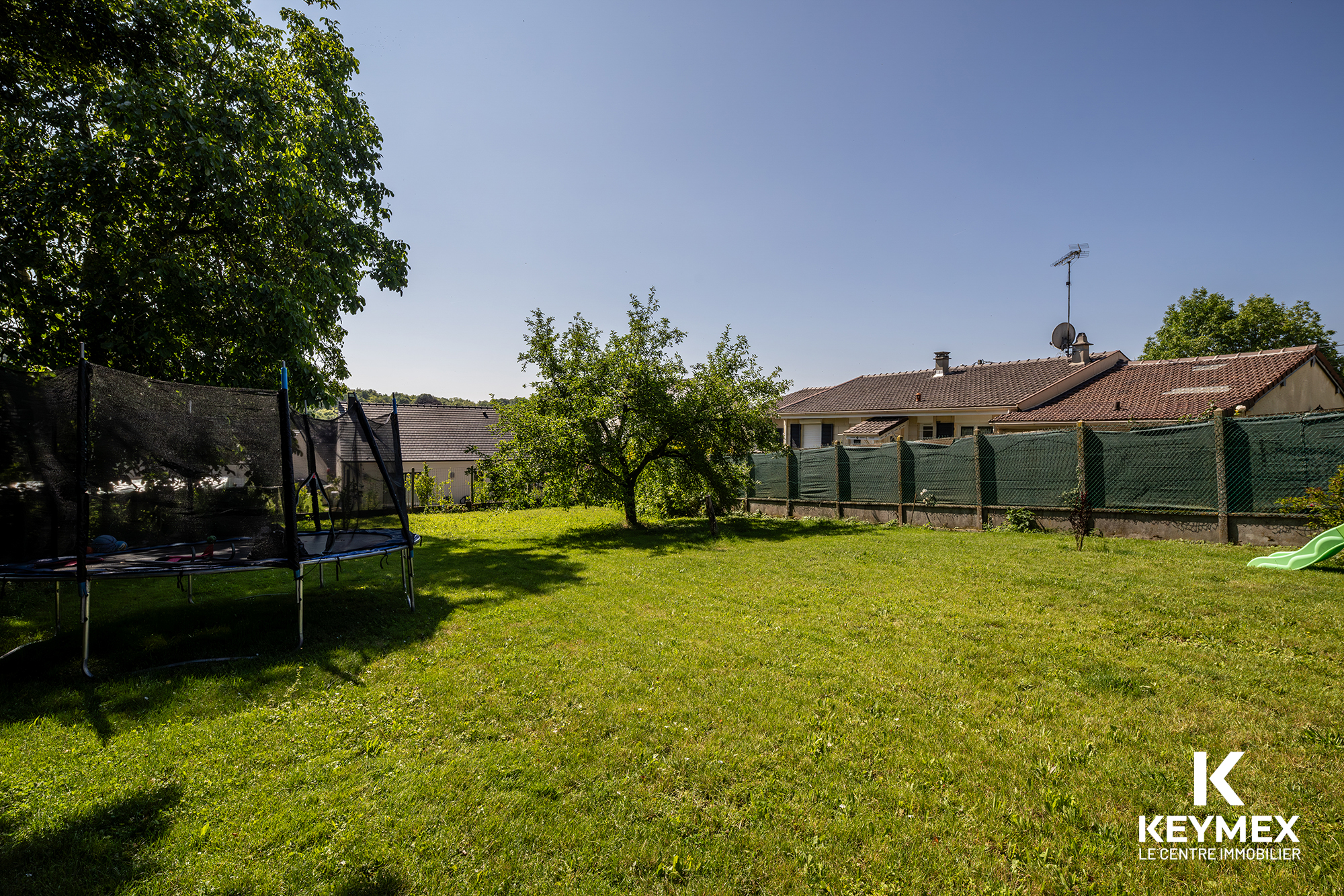 Jardin avec trampoline et maisons en arrière-plan