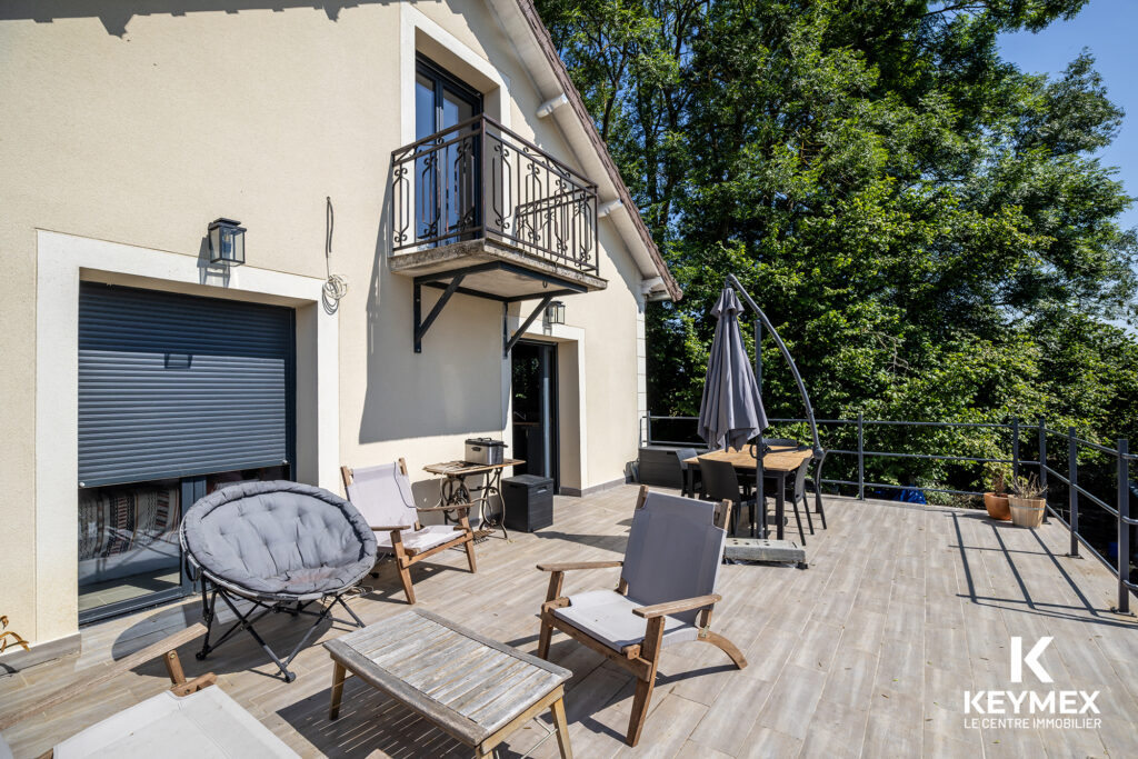 Terrasse ensoleillée avec meubles en bois et parasol.