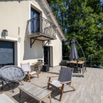 Terrasse ensoleillée avec meubles en bois et parasol.