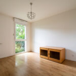 Chambre lumineuse avec parquet et armoire bois.