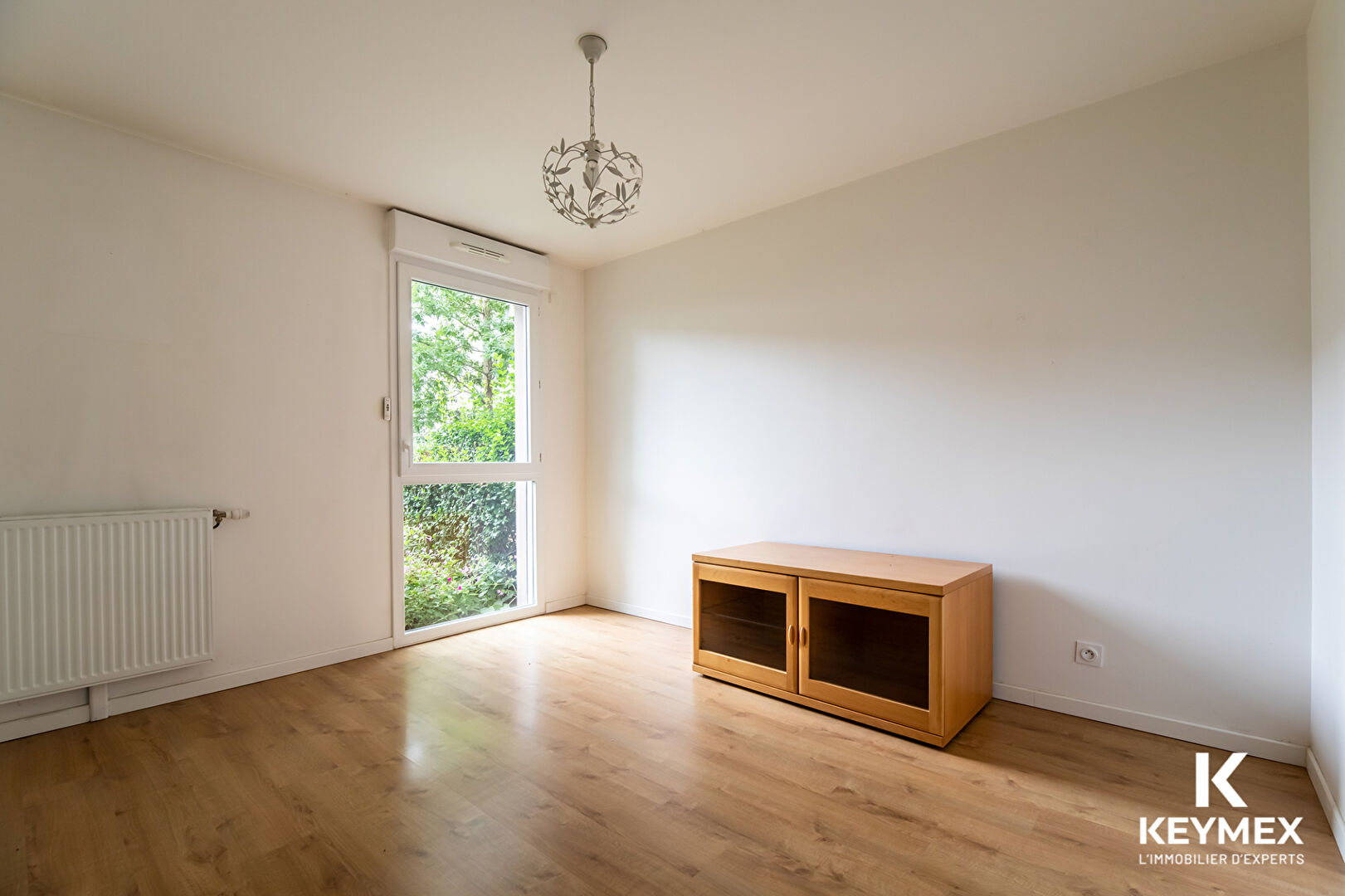 Chambre lumineuse avec parquet et armoire bois.