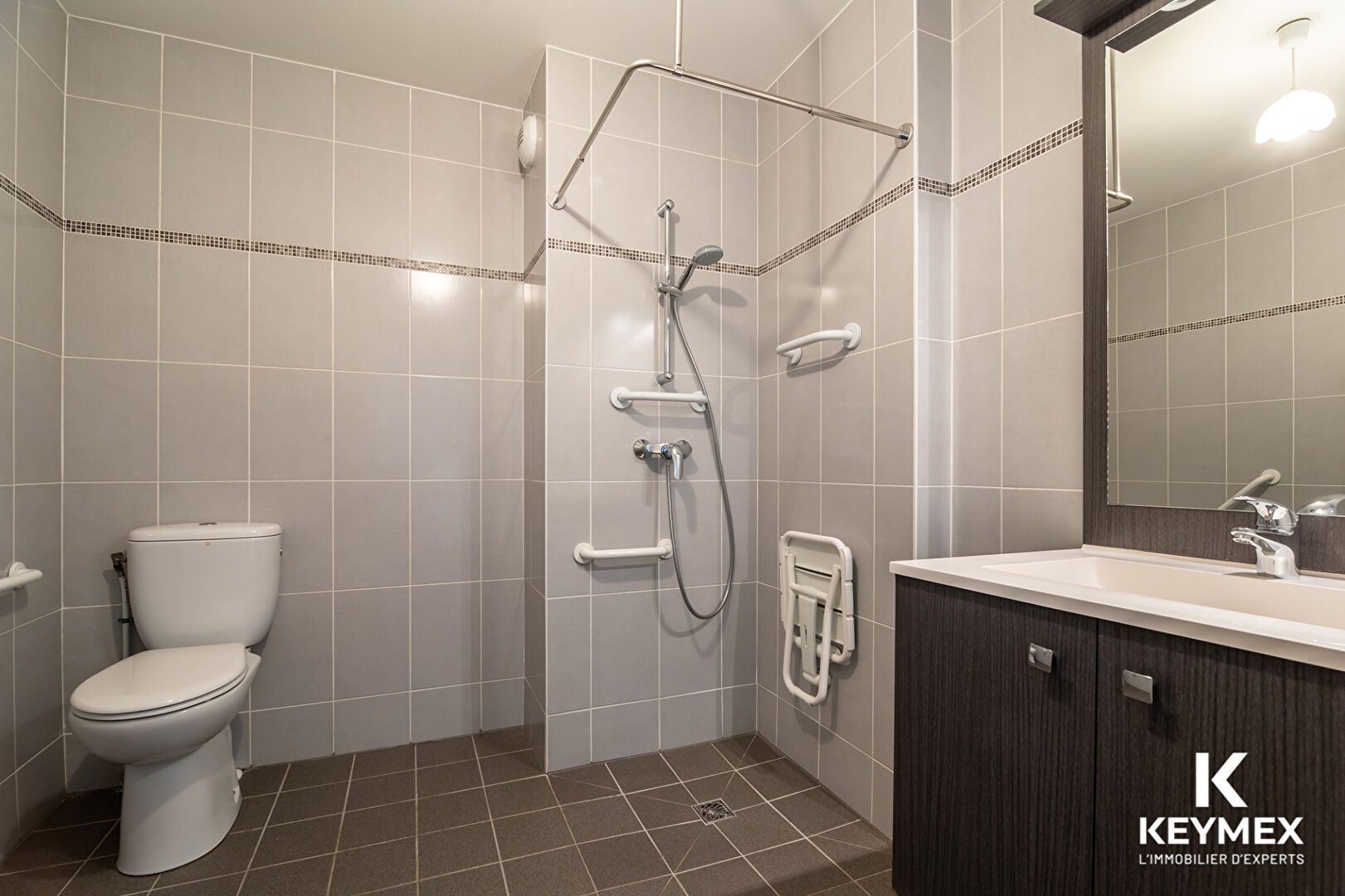 Salle de bain adaptée avec douche sécurisée.
