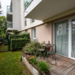 Balcon avec table et chaise, vue sur jardin.