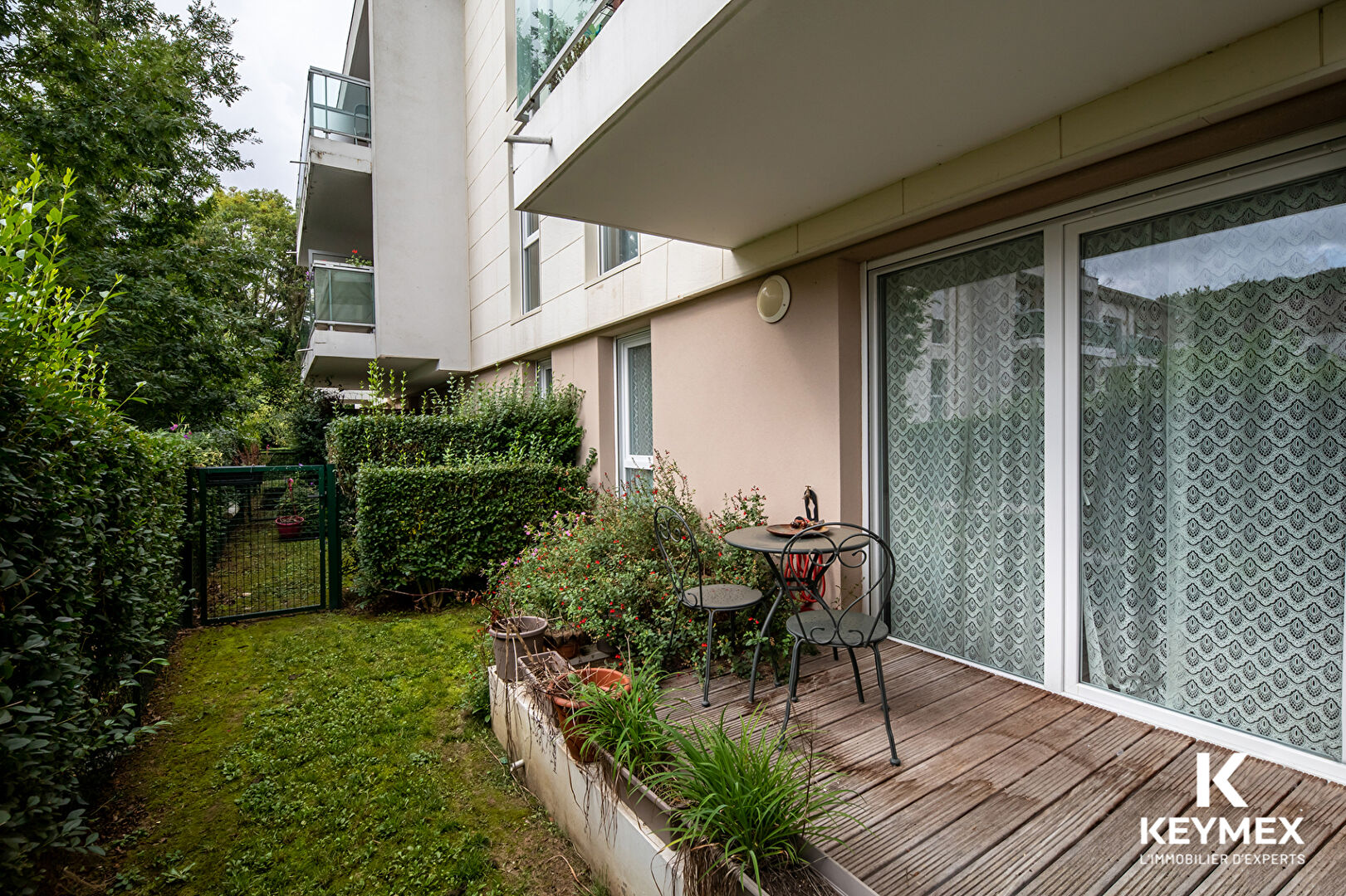 Balcon avec table et chaise, vue sur jardin.