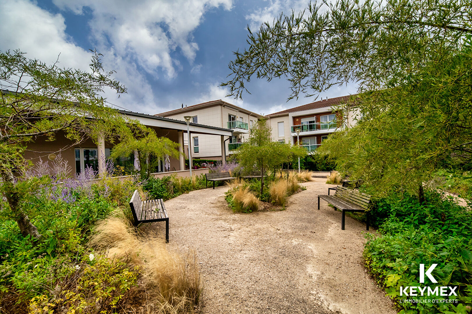 Jardin paisible avec bancs et végétation luxuriante.