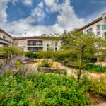 Jardin résidentiel verdoyant avec bancs et immeubles.