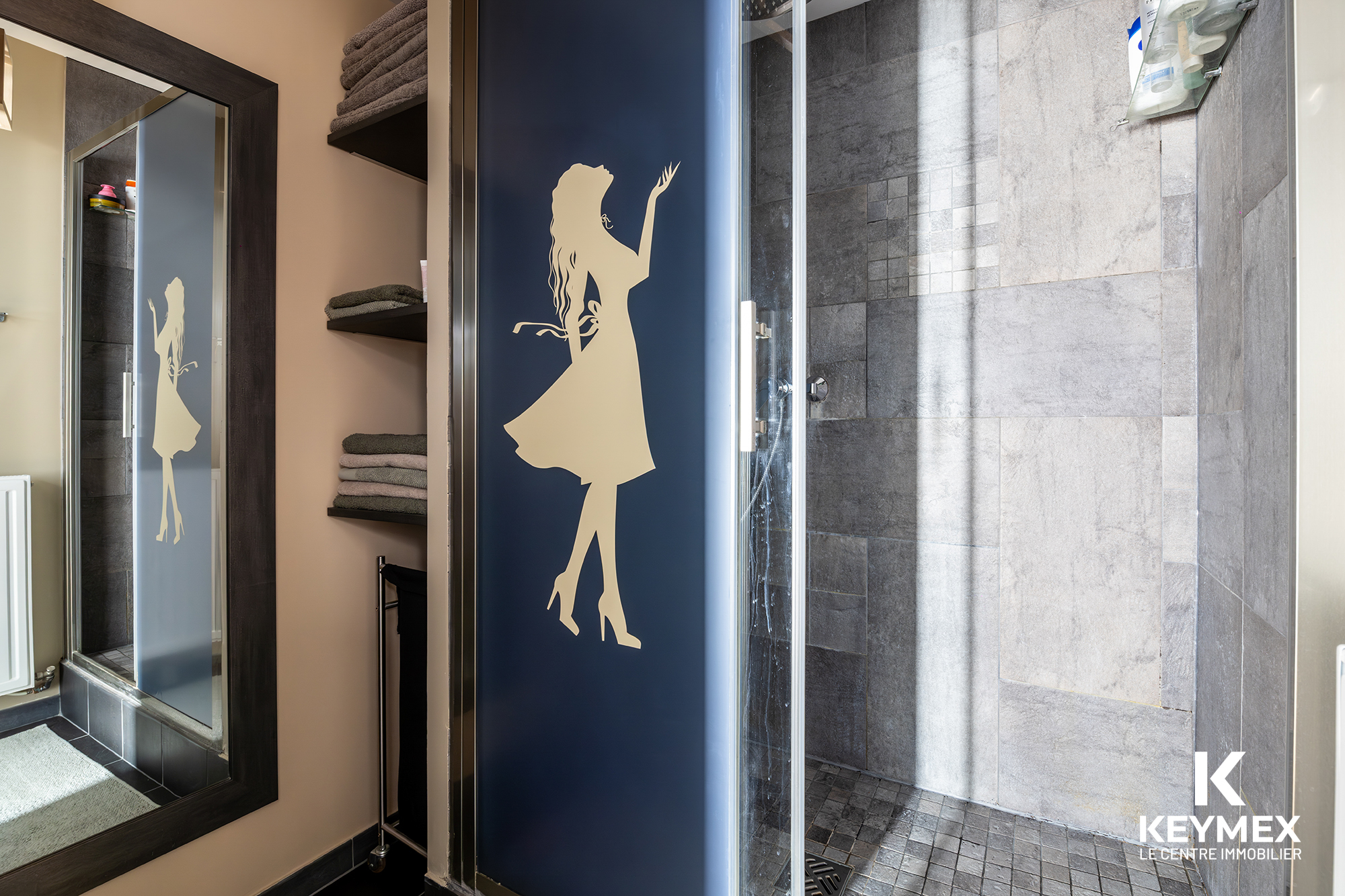 Salle de bain moderne avec douche et miroir.