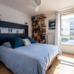 Chambre lumineuse avec lit, étagères, fenêtre, décoration moderne.