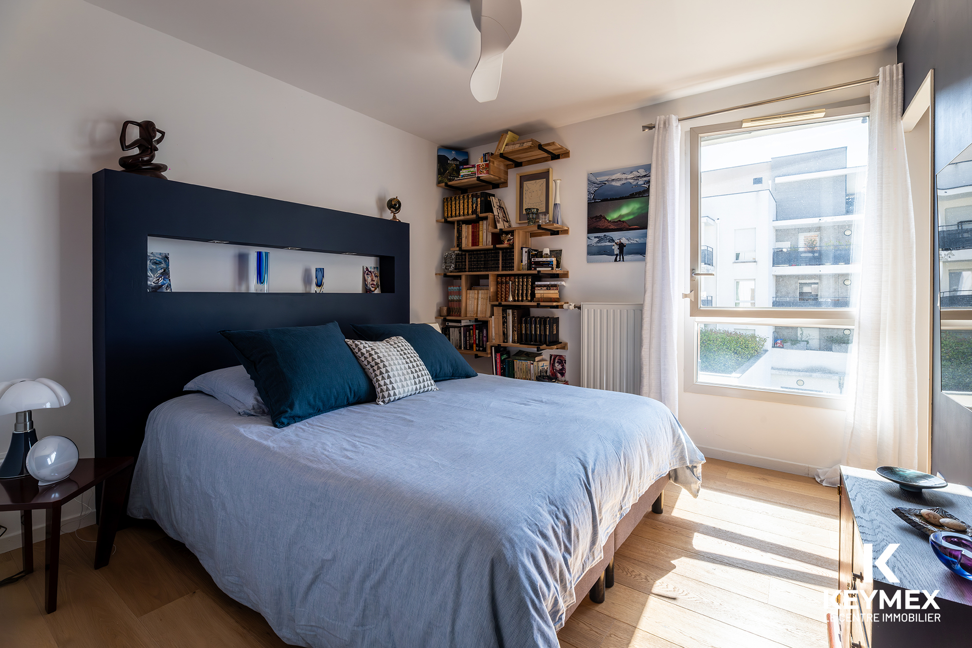 Chambre lumineuse avec lit, étagères, fenêtre, décoration moderne.