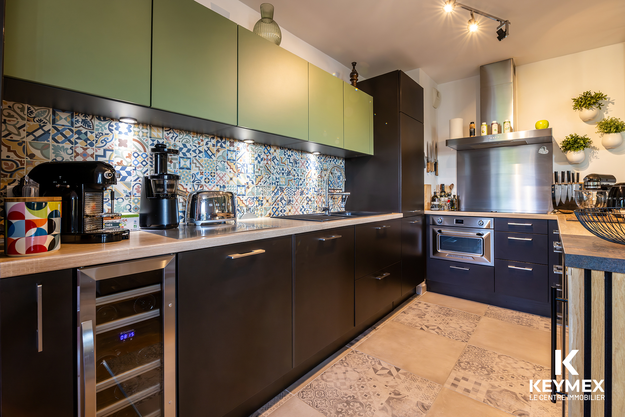 Cuisine moderne avec carreaux colorés et électroménager.