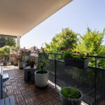 Balcon fleuri avec vue sur jardin verdoyant.