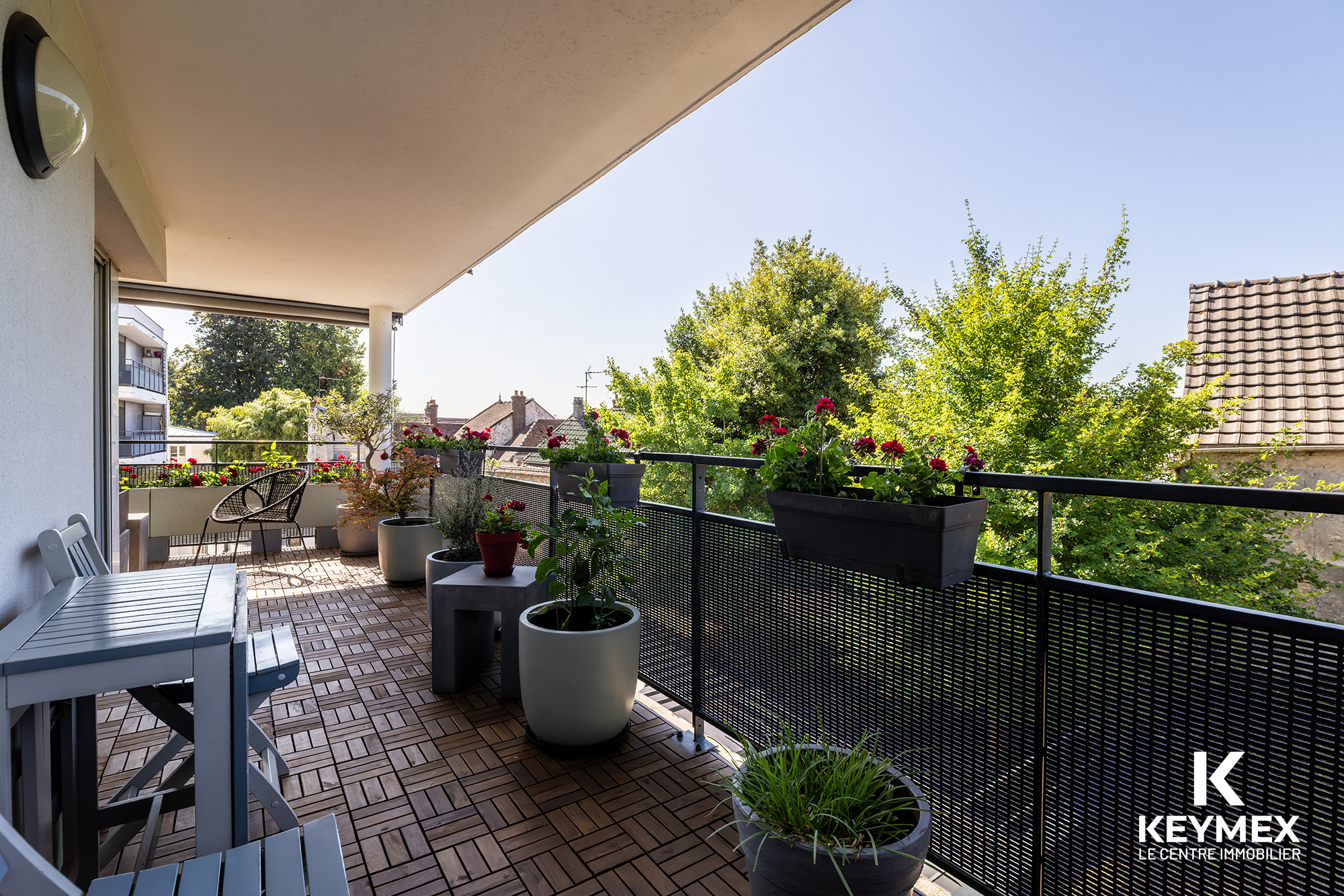 Balcon fleuri avec vue sur jardin verdoyant.