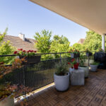 Terrasse fleurie avec vue sur arbres et maisons.