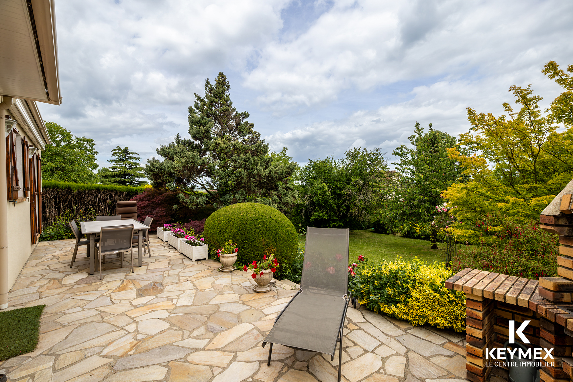 Terrasse jardin avec mobilier extérieur et plantes.