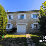 Maison en pierre avec volets blancs et jardin