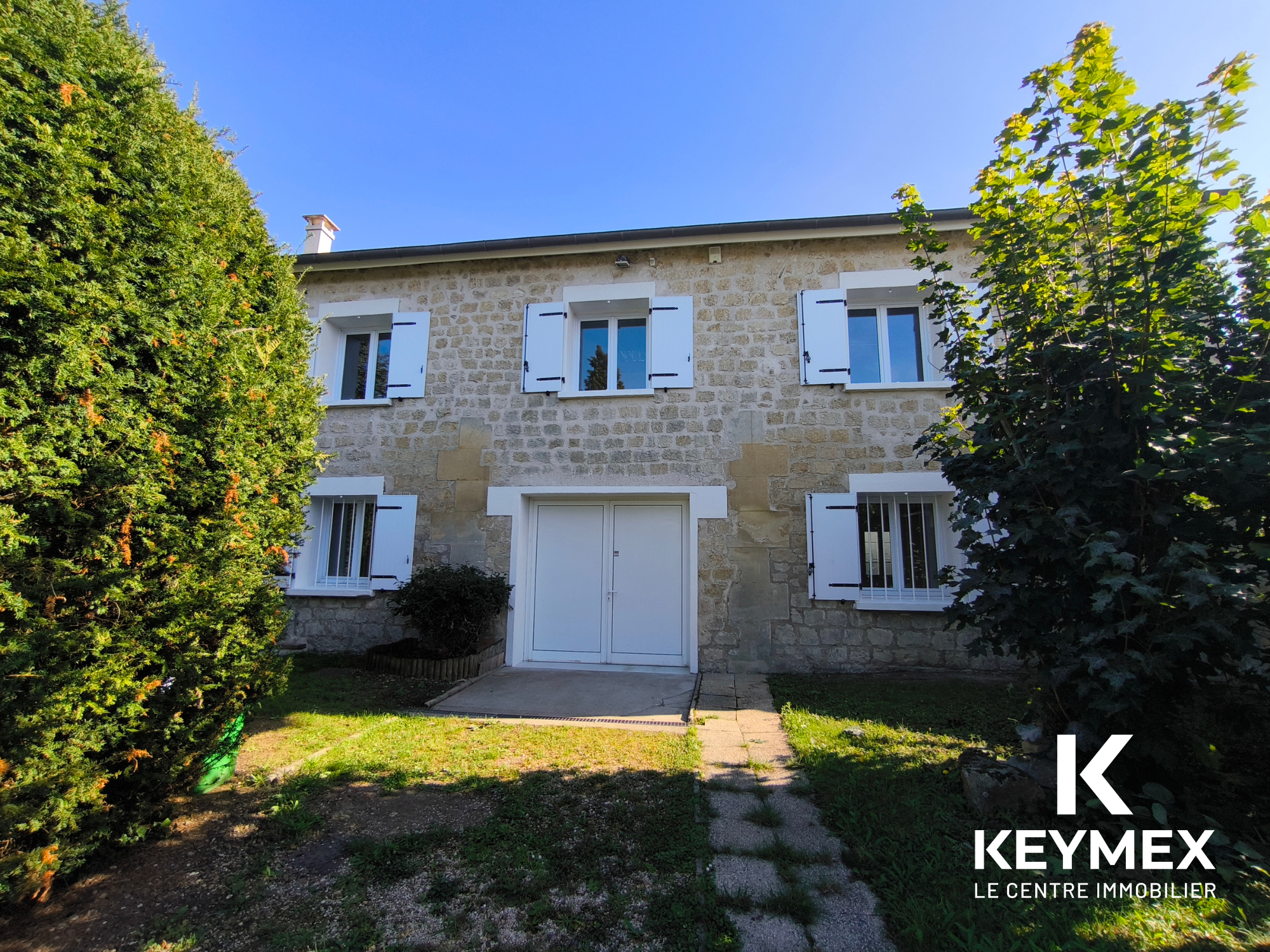 Maison en pierre avec volets blancs et jardin