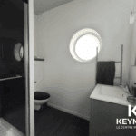 Salle de bain moderne avec douche et lavabo.