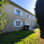 Maison en pierre avec volets blancs ouverte au soleil