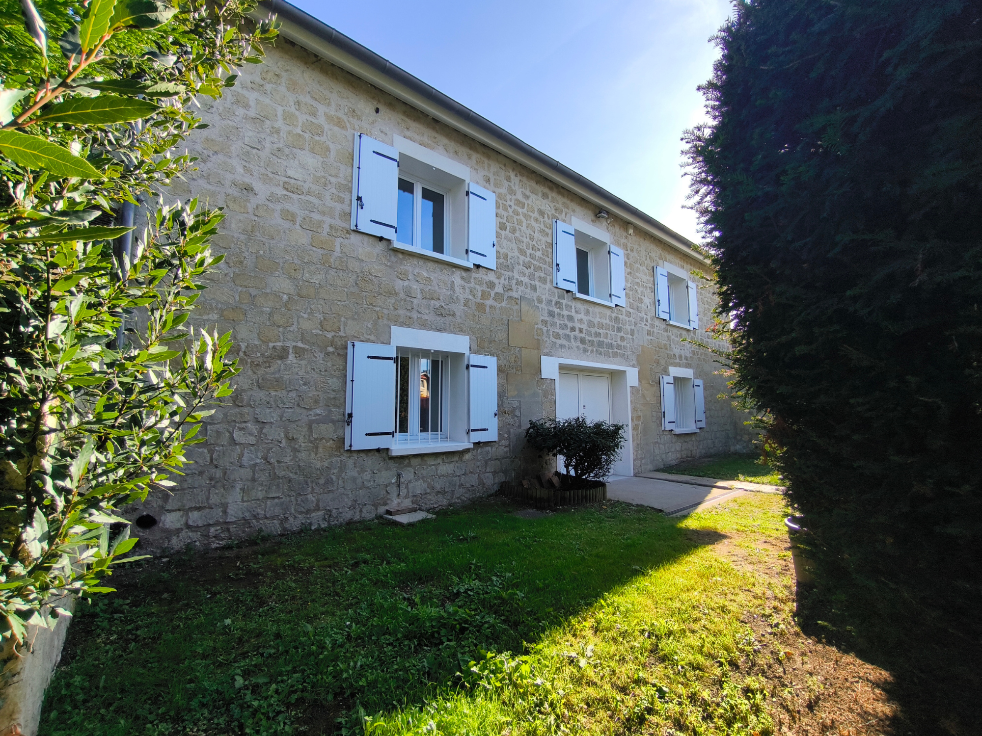 Maison en pierre avec volets blancs ouverte au soleil