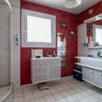 Salle de bain moderne rouge et blanche, douche et meubles.