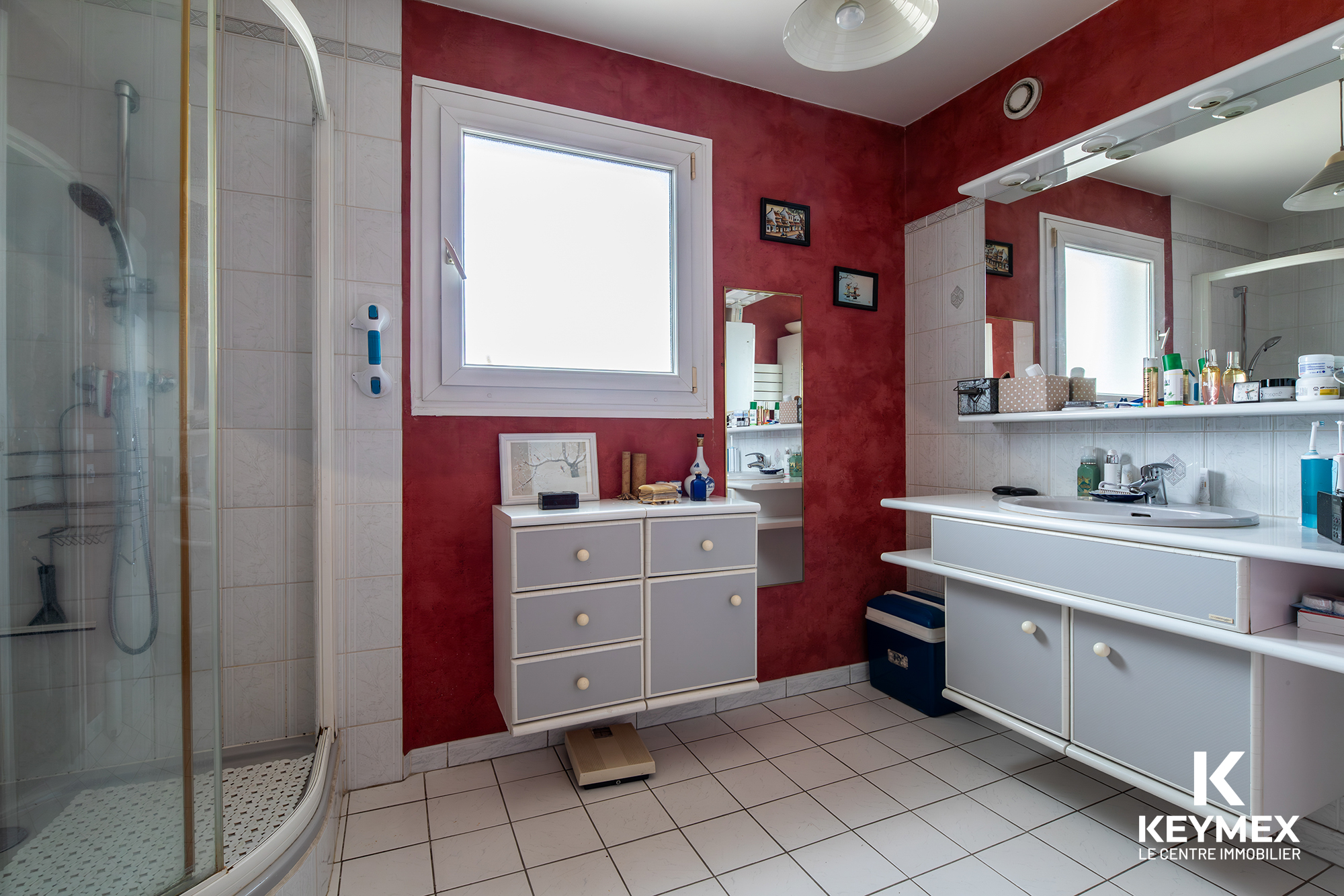 Salle de bain moderne rouge et blanche, douche et meubles.
