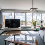 Salon moderne avec grande baie vitrée et terrasse.