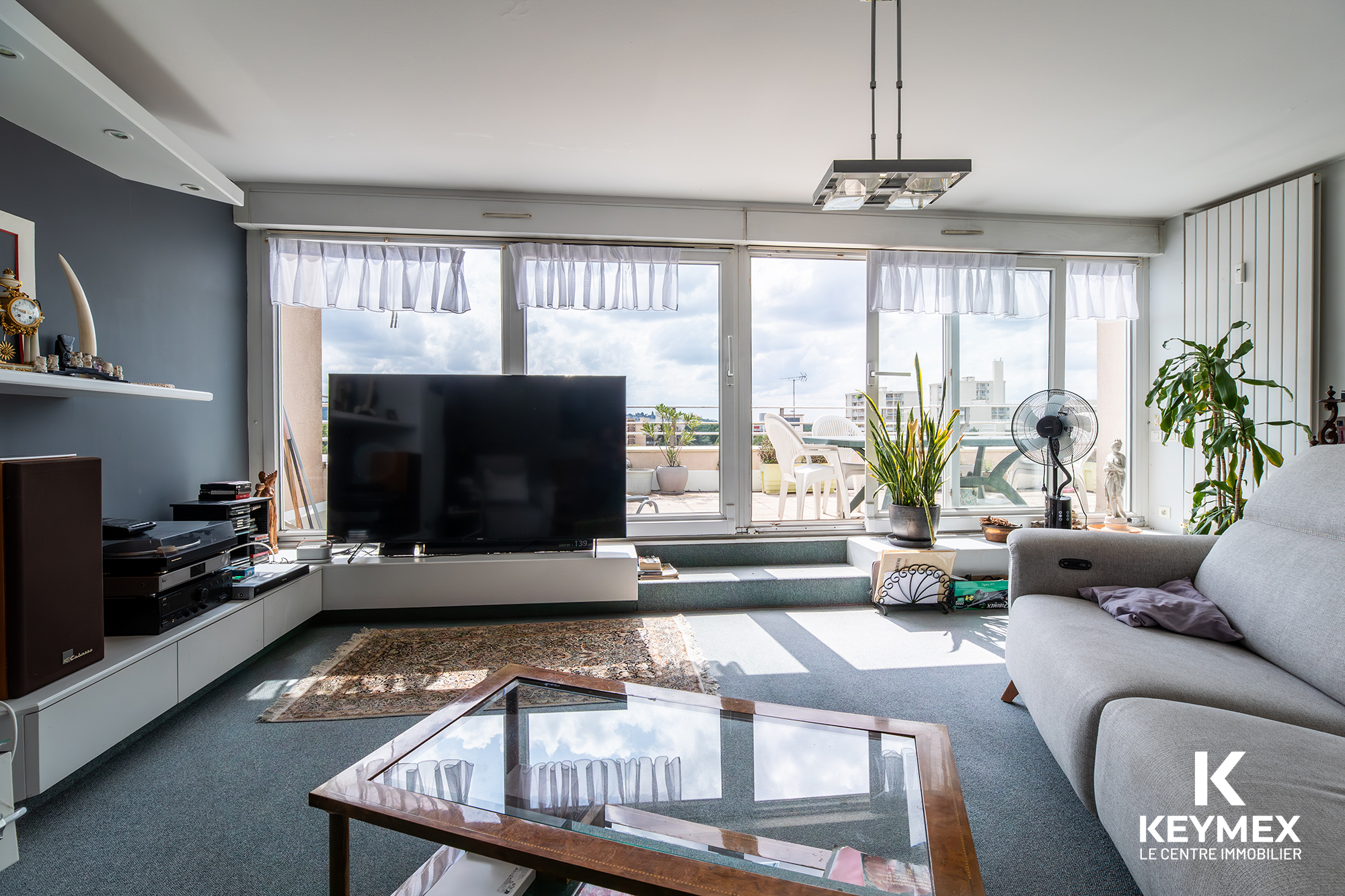Salon moderne avec grande baie vitrée et terrasse.