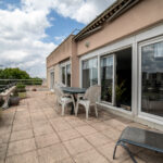 Grande terrasse extérieure avec mobilier de jardin.